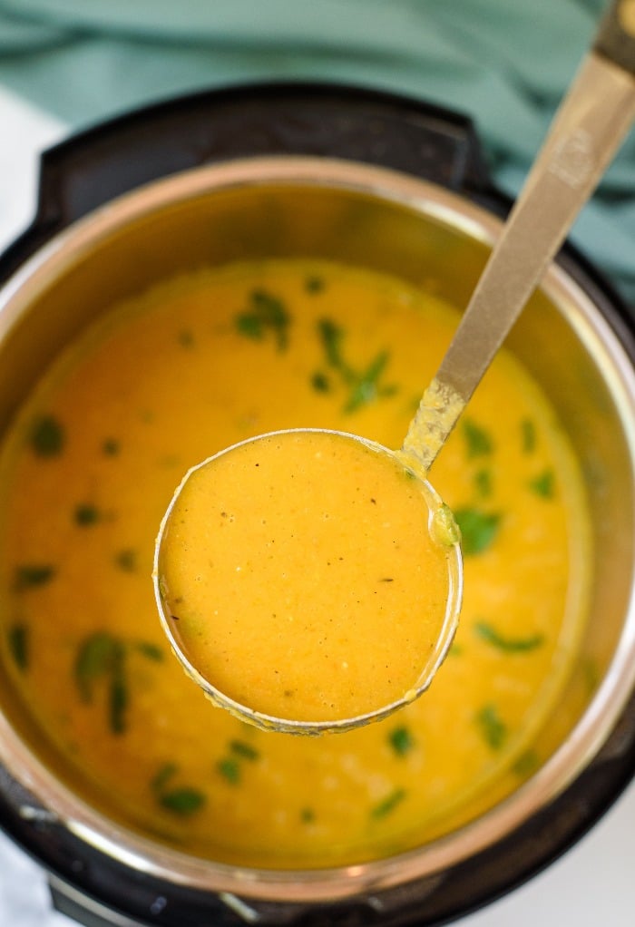 A ladle full of butternut squash soup made in an Instant Pot. 