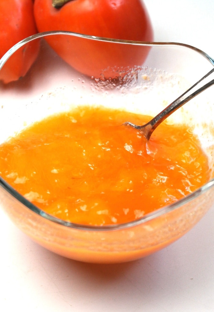 The pulp of ripe persimmon in a clear bowl. 