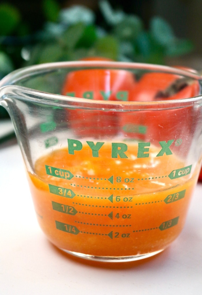 The pulp of persimmon in a clear pyrex measuring cup. 