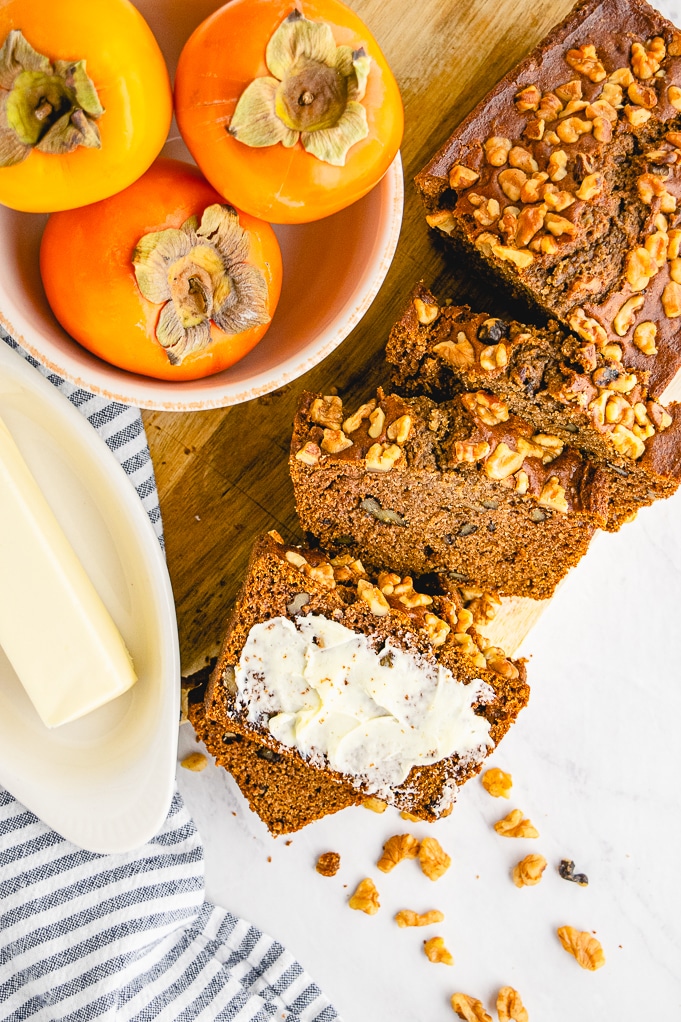 Top view of a loaf of persimmon bread topped with walnuts. 