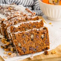 A loaf of persimmon bread sliced on a cutting board.