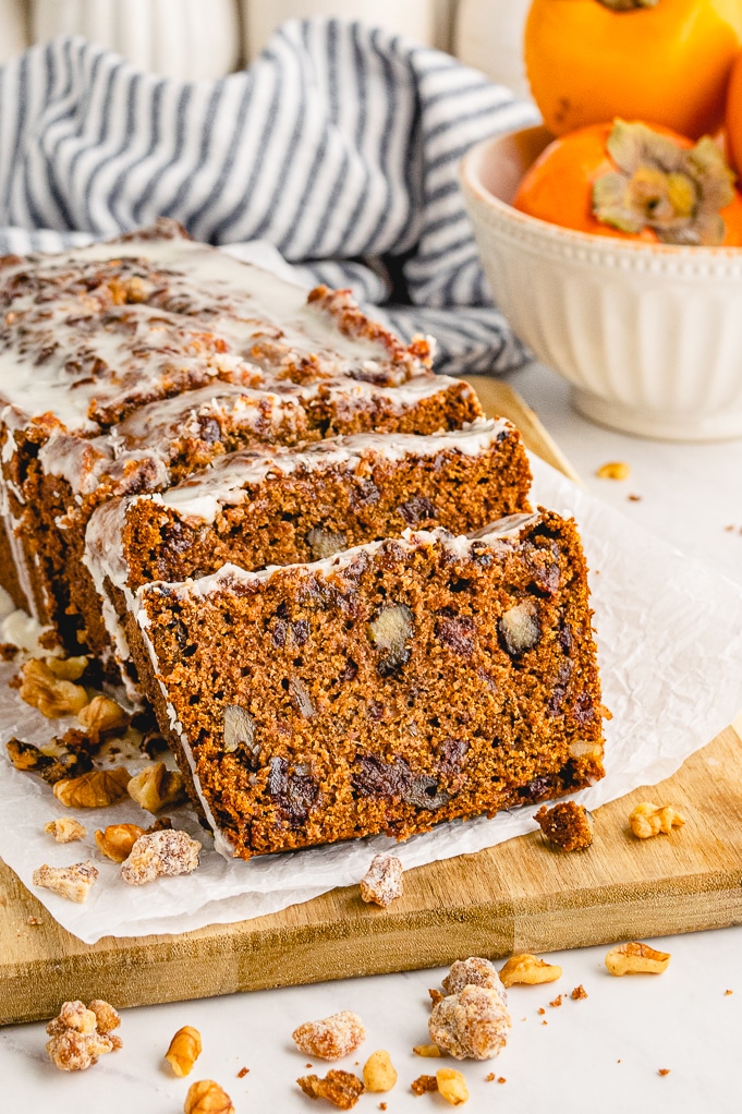 A loaf of persimmon bread sliced on a cutting board.