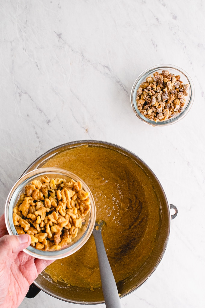 Top view of chopped nuts being added to bread batter.