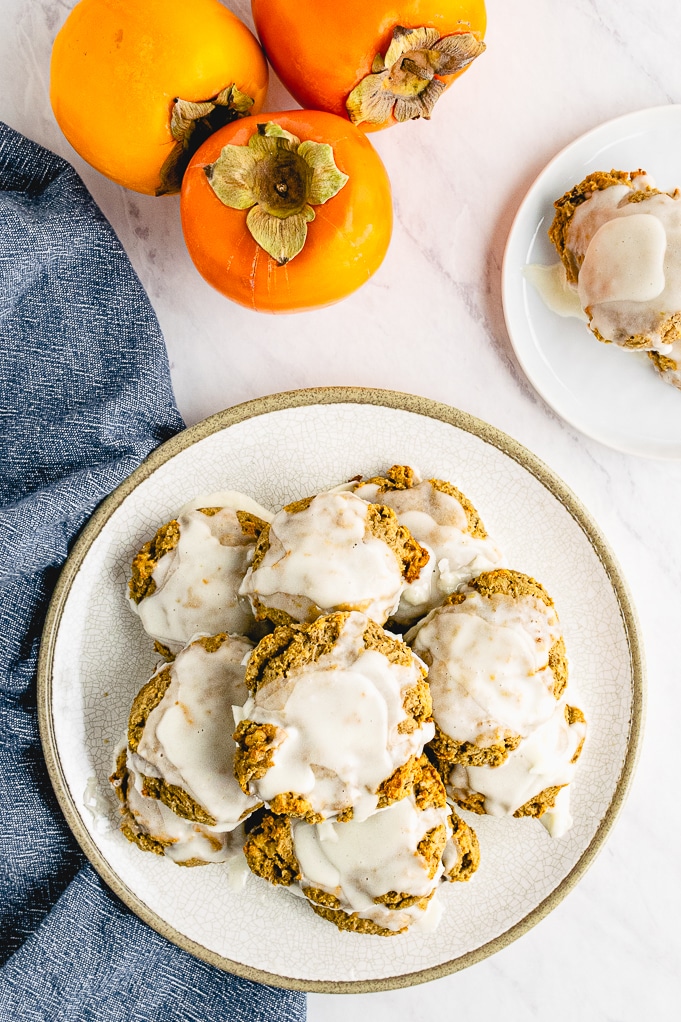 Top view of persimmon cookies on a white plate topped with glaze.