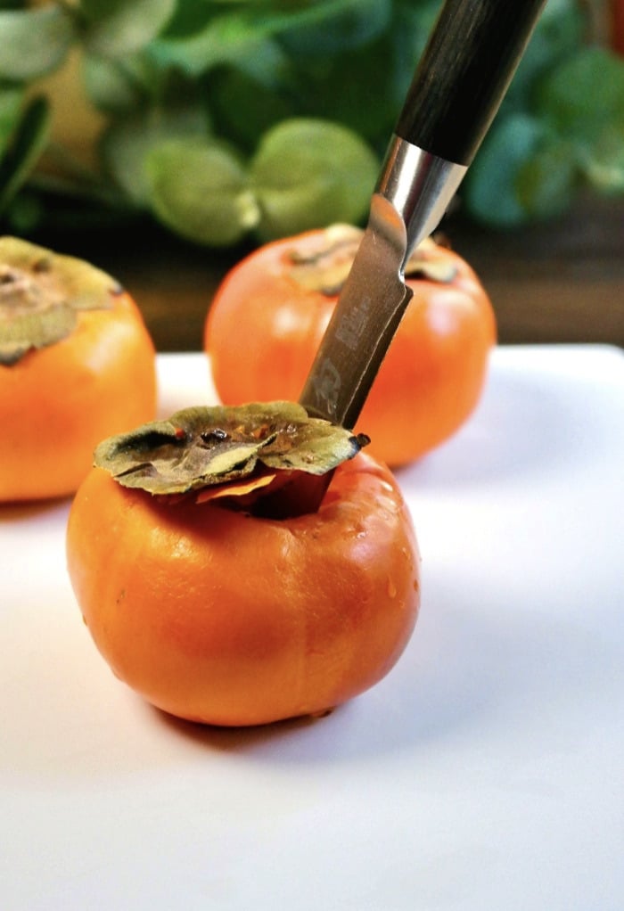 Cut the tops off of a persimmon before slicing