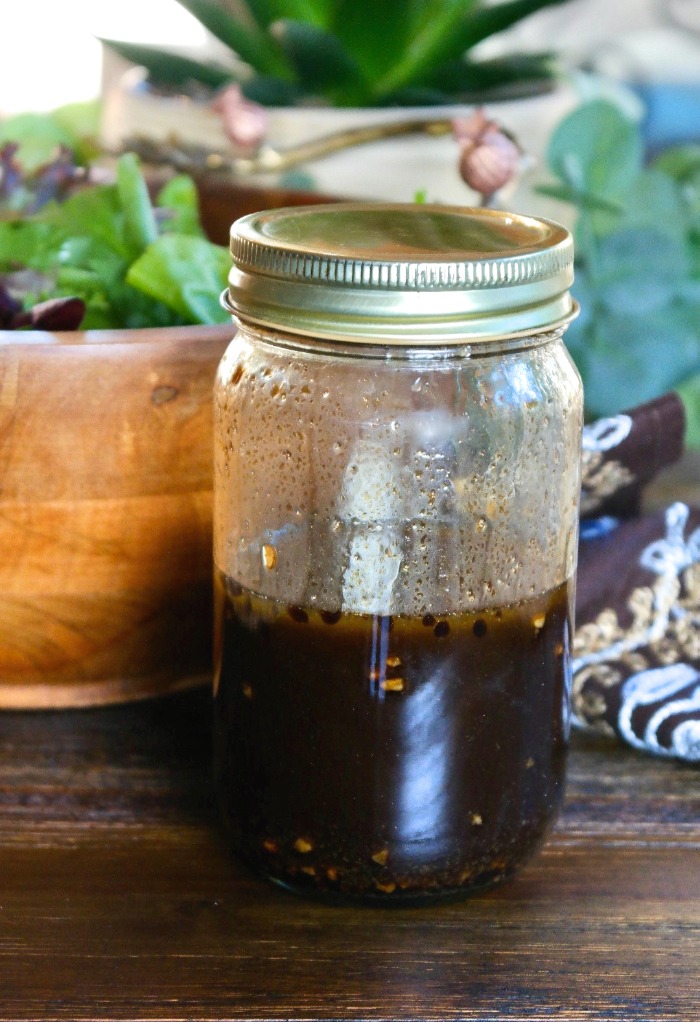 A jar with a gold lid filled with balsamic vinaigrette. 