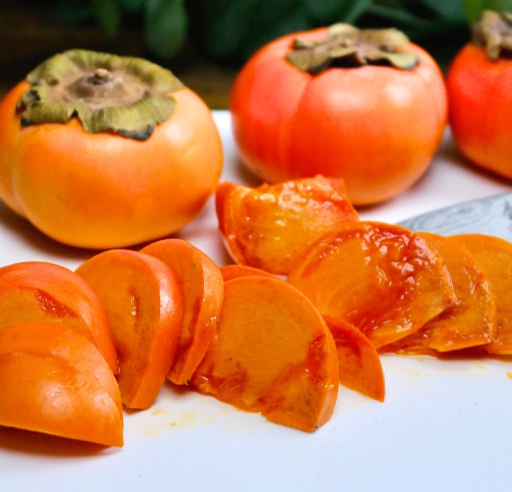 sliced fuyu persimmon on a white cutting board. 