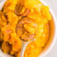 Top view of a spoonful of mashed sweet potatoes with sausage for breakfast.