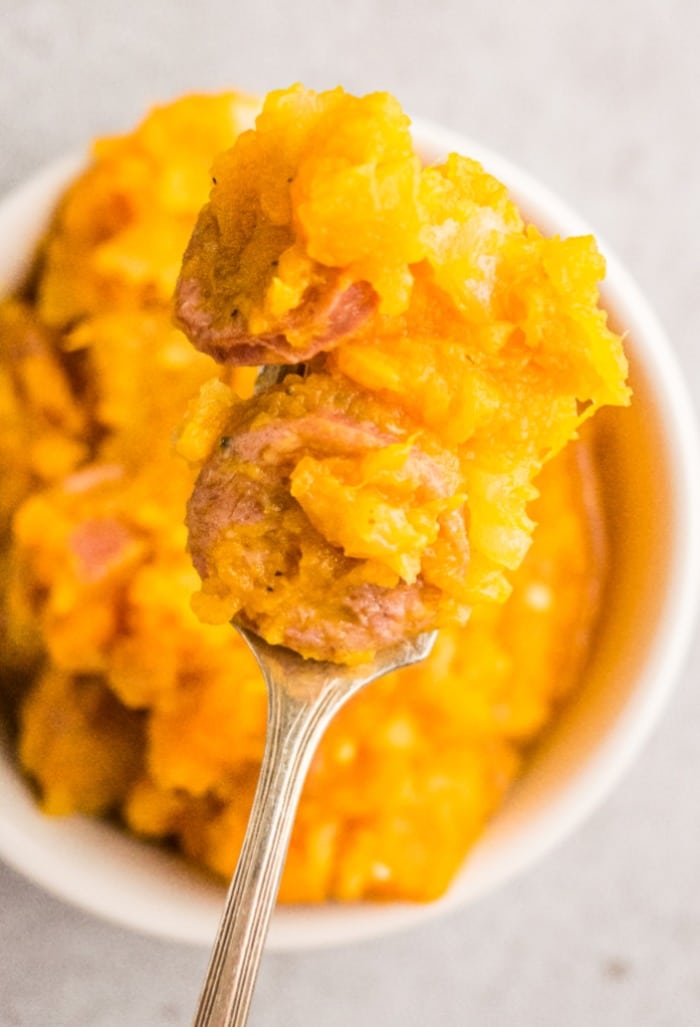 Top view of a spoonful of mashed sweet potatoes with sausage for breakfast.