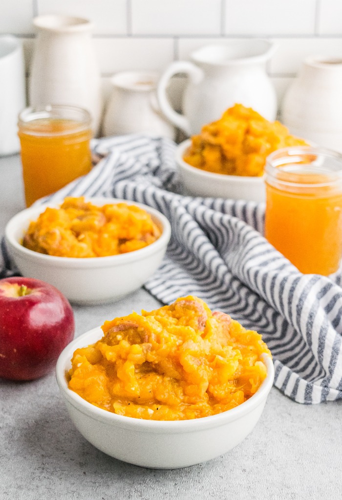 White serving bowls with mashed sweet potatoes, apple and sausage for a filling savory breakfast.