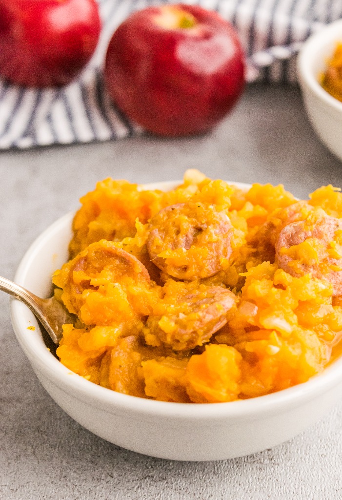 Finished mashed sweet potatoes with sausage in a white serving bowl. 