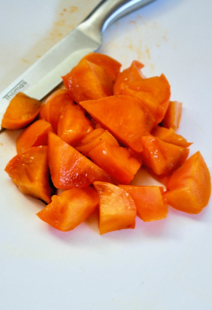 Diced persimmons on a white cutting board. 