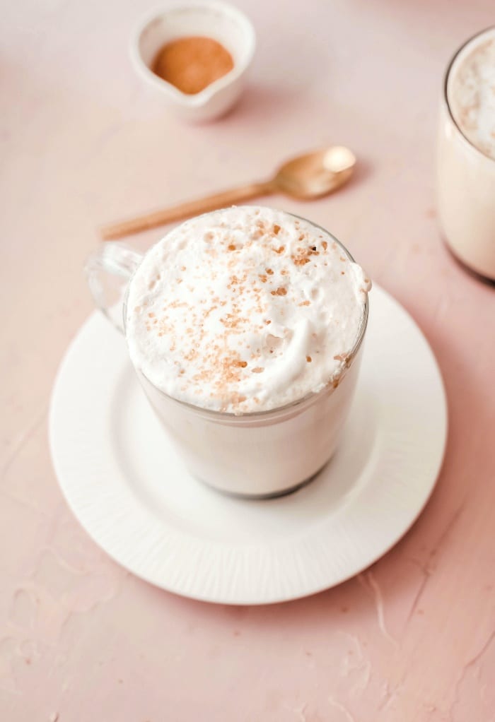 Top view of coffee latte topped with fresh whipped cream in a clear glass mug ready to enjoy. 