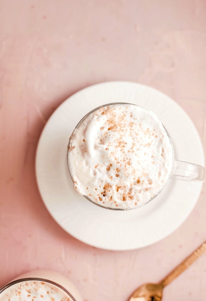 A top view of a latte with a spoon on the side. 