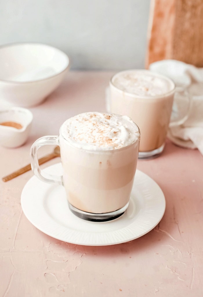 Clear coffee mugs filled with latte topped with whipped cream. 