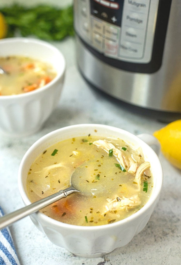 A white bowl with a spoonful of chicken soup ready to be eaten. 