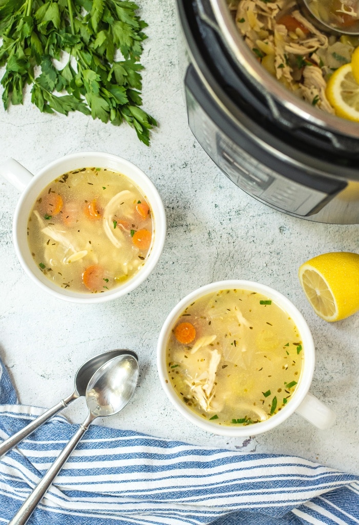 Top view of two white bowls filled with chicken soup with an Instant Pot on the side. 