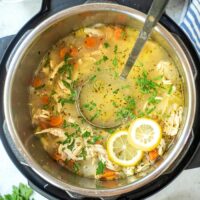 Cooked lemon chicken orzo soup in an Instant Pot with a large spoon ready to scoop into bowls.