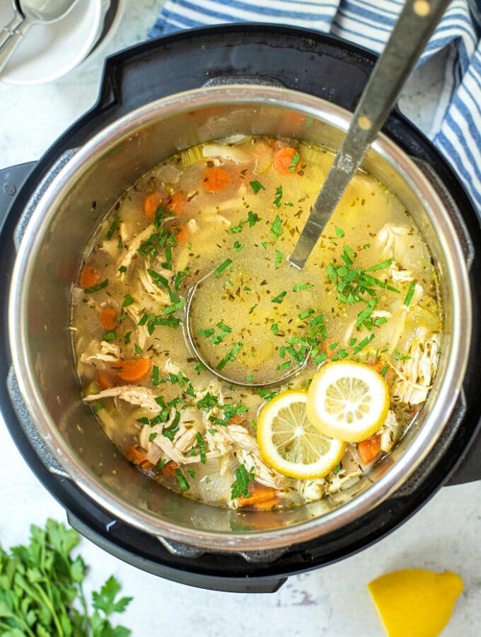 Cooked lemon chicken orzo soup in an Instant Pot with a large spoon ready to scoop into bowls.