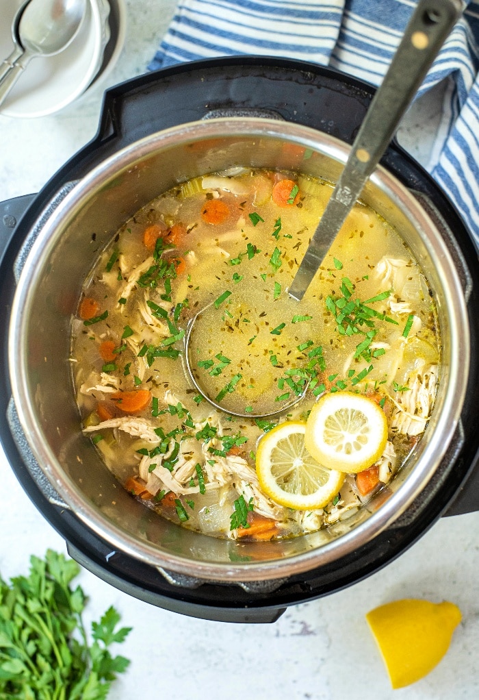 Cooked lemon chicken orzo soup in an Instant Pot with a large spoon ready to scoop into bowls.