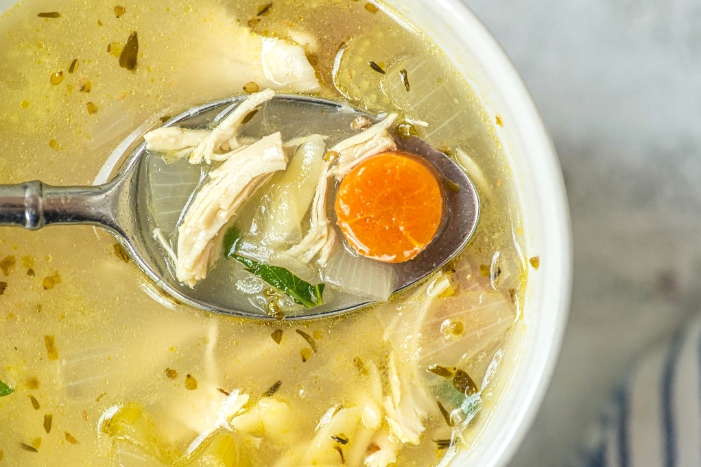 Close spoonful view of lemon chicken orzo soup.