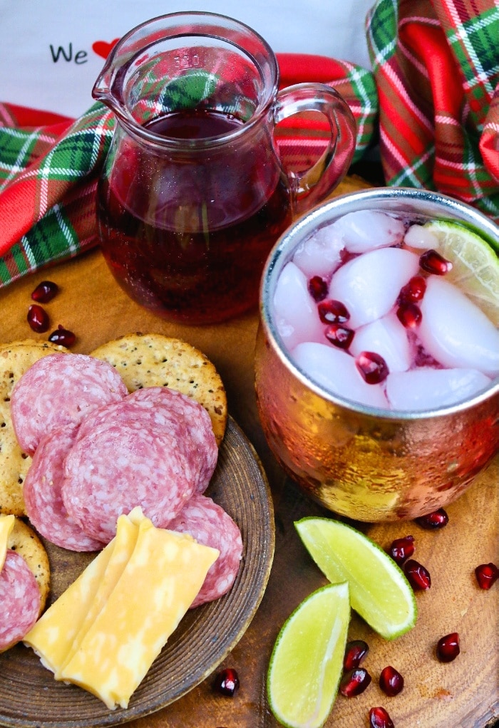 Cocktail in a copper mug with cheese and salami ready to be eaten.