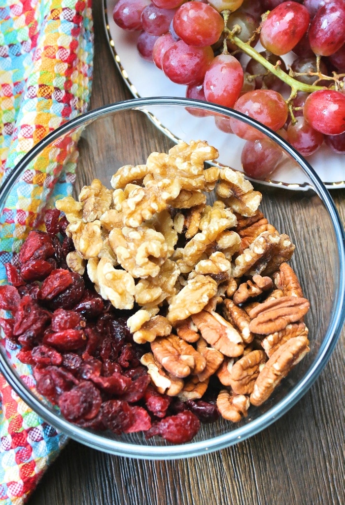 A clear bowl with cranberries and walnut.s