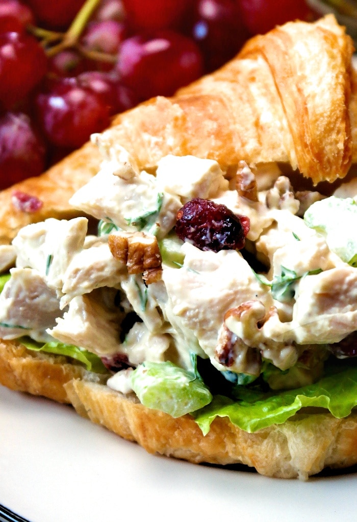 A turkey salad sandwich with croissant bread on a white plate.