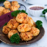 Stacked potato balls on a brown serving plate with parsley ready to eat.