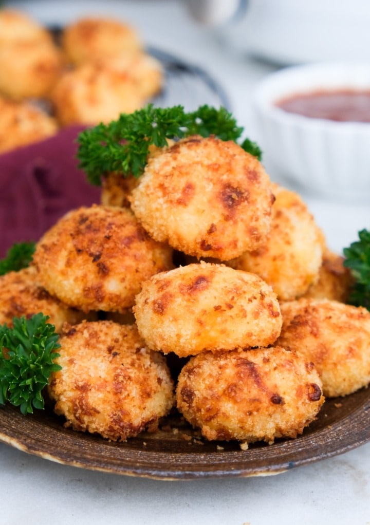 Air fryer mashed potato balls on a brown serving plate.