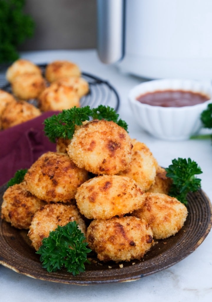 Mashed potato balls stacked on a brown serving plate. 