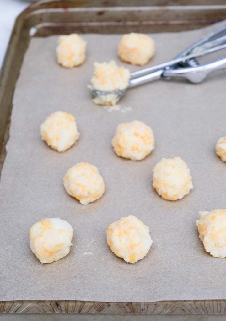 Potato balls shaped into balls with a small cookie scoop on a parchment lined baking sheet. 