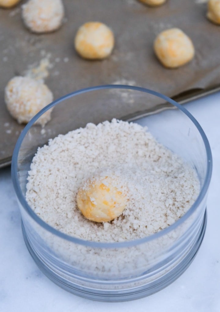 Mashed potato balls rolled in panko flakes in a clear bowl.