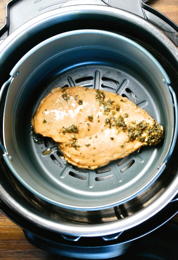 A top view of chicken breast in an air fryer ready to cook.