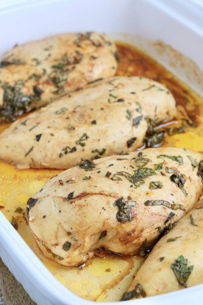 A white baking dish with cooked chicken breasts. 