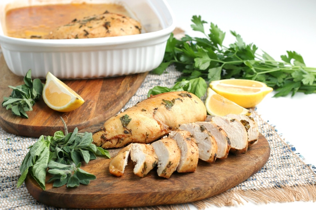 A horizontal view of sliced chicken on a brown wood cutting board ready to enjoy. 