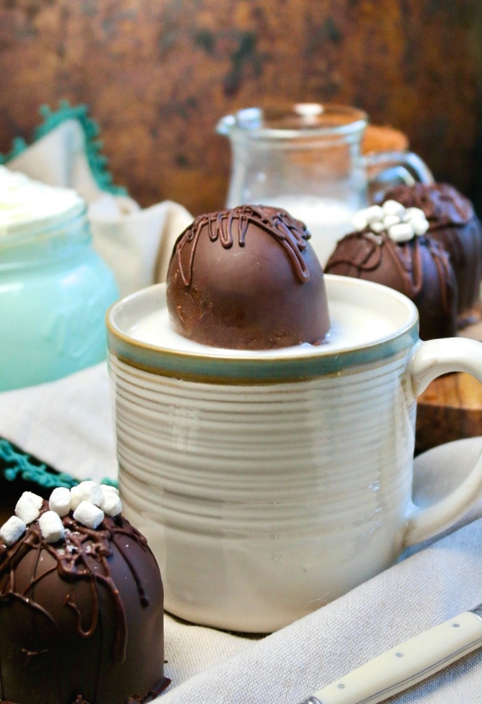 A mug with a hot chocolate bomb poking out ready to be turned into a beverage. 