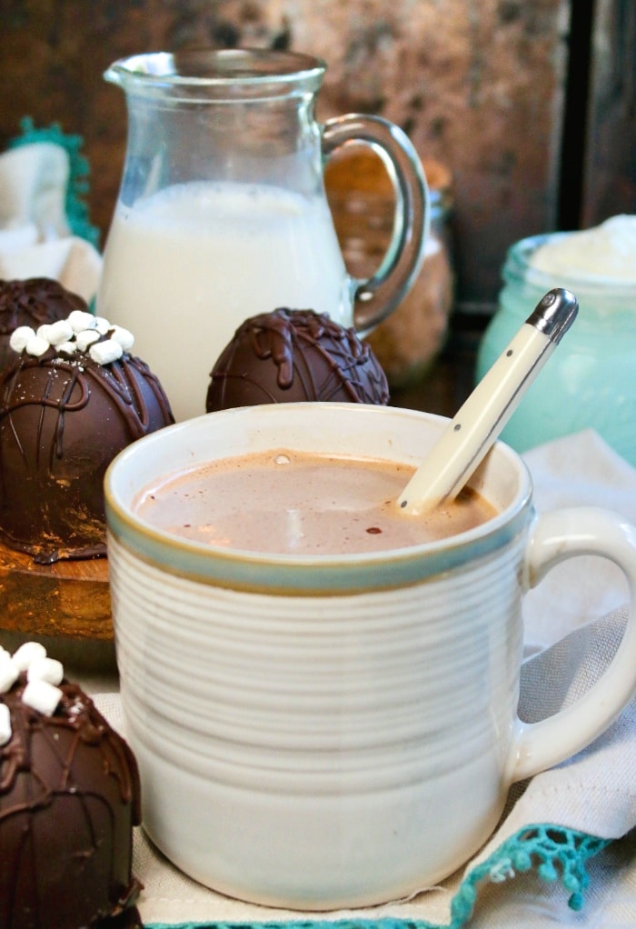 Hot chocolate in a cream mug with a spoon in the middle to stir.