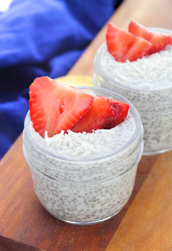 Small mason jars filled with coconut chia pudding topped with fresh strawberries. 