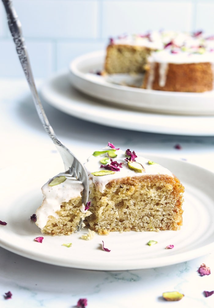 A slice of Persian love cake on a white plate with a fork digging into it ready to eat. 