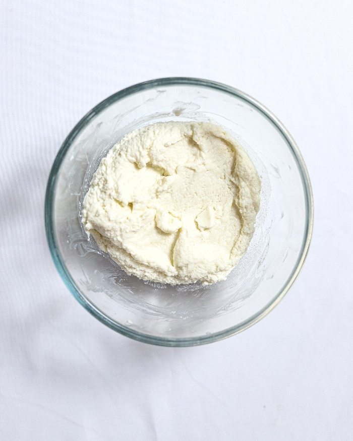 Yogurt in a clear mixing bowl, which is part of a cake recipe.