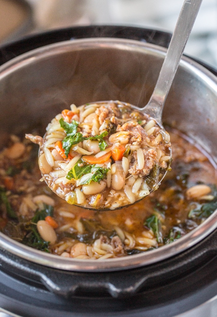 Ladle full of Italian sausage soup ready to put in serving bowls.