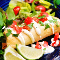 Shredded Beef Chimichanga on a blue plate topped with sour cream and tomatoes.