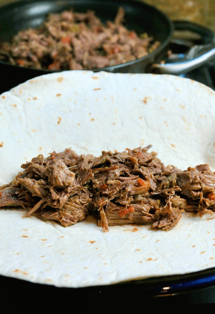 Shredded beef in the middle of a tortilla ready to fold to put in a air fryer. 