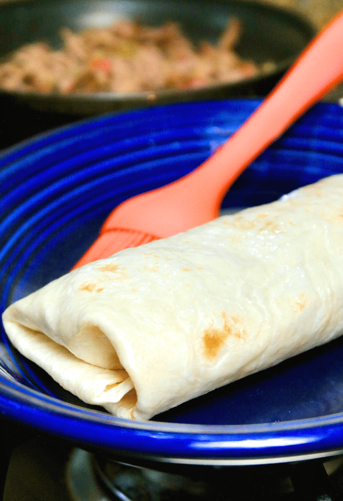 Here is a folded chimichanga lightly coated with oil before cooking in an air fryer. 