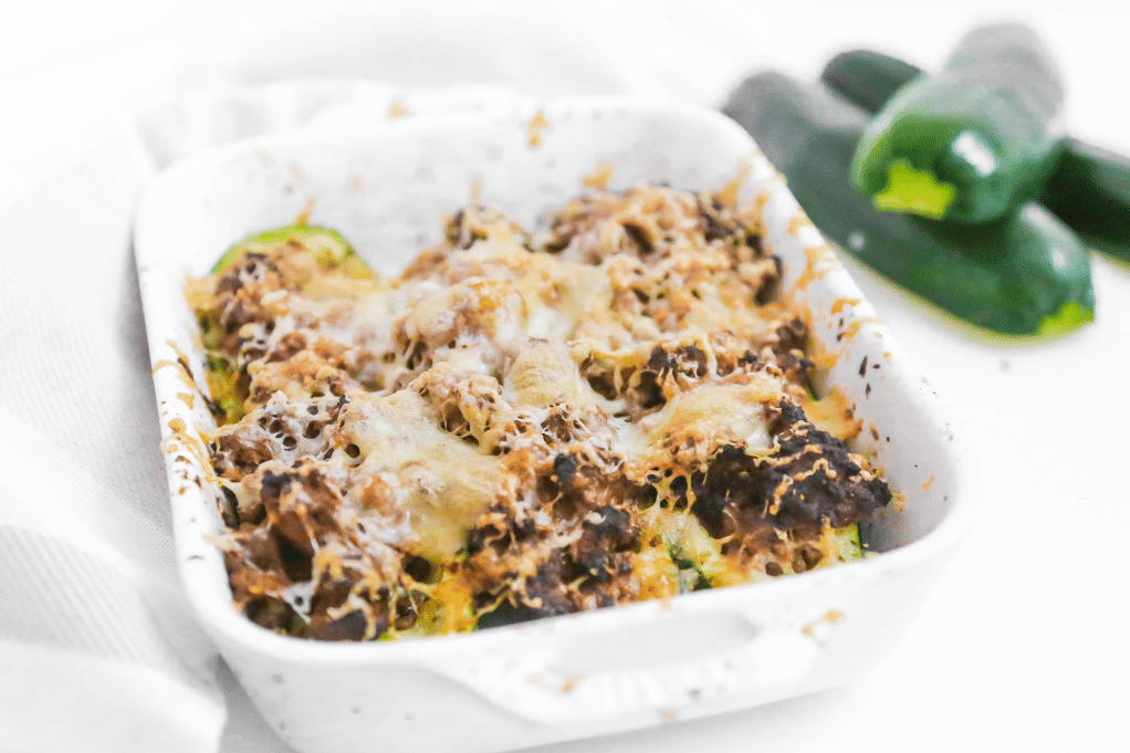 Air fryer zucchini stuffed with cooked hamburger with Italian spices in a white baking dish ready to enjoy.