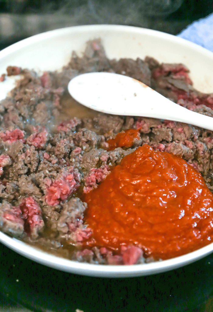 A skillet with hamburger and tomato sauce.