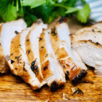 Sliced air fryer chicken breast with no breading on a cutting board.