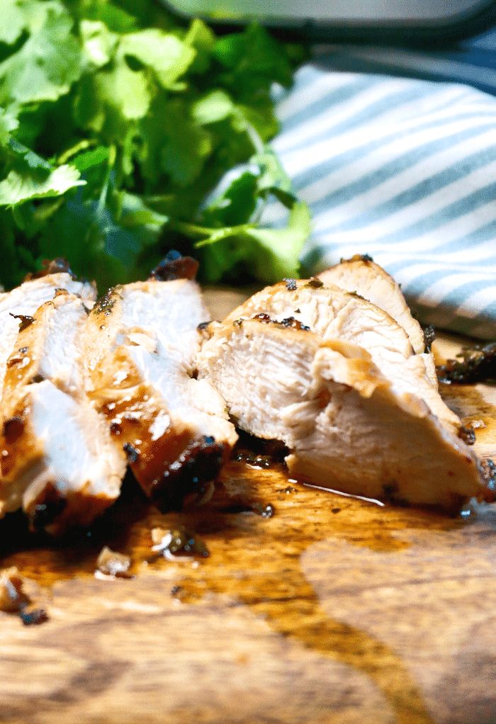 Tender chicken breast cooked in an air fryer on a wood cutting board. 