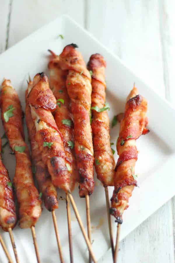 Top view of bacon wrapped skewers on a white plate